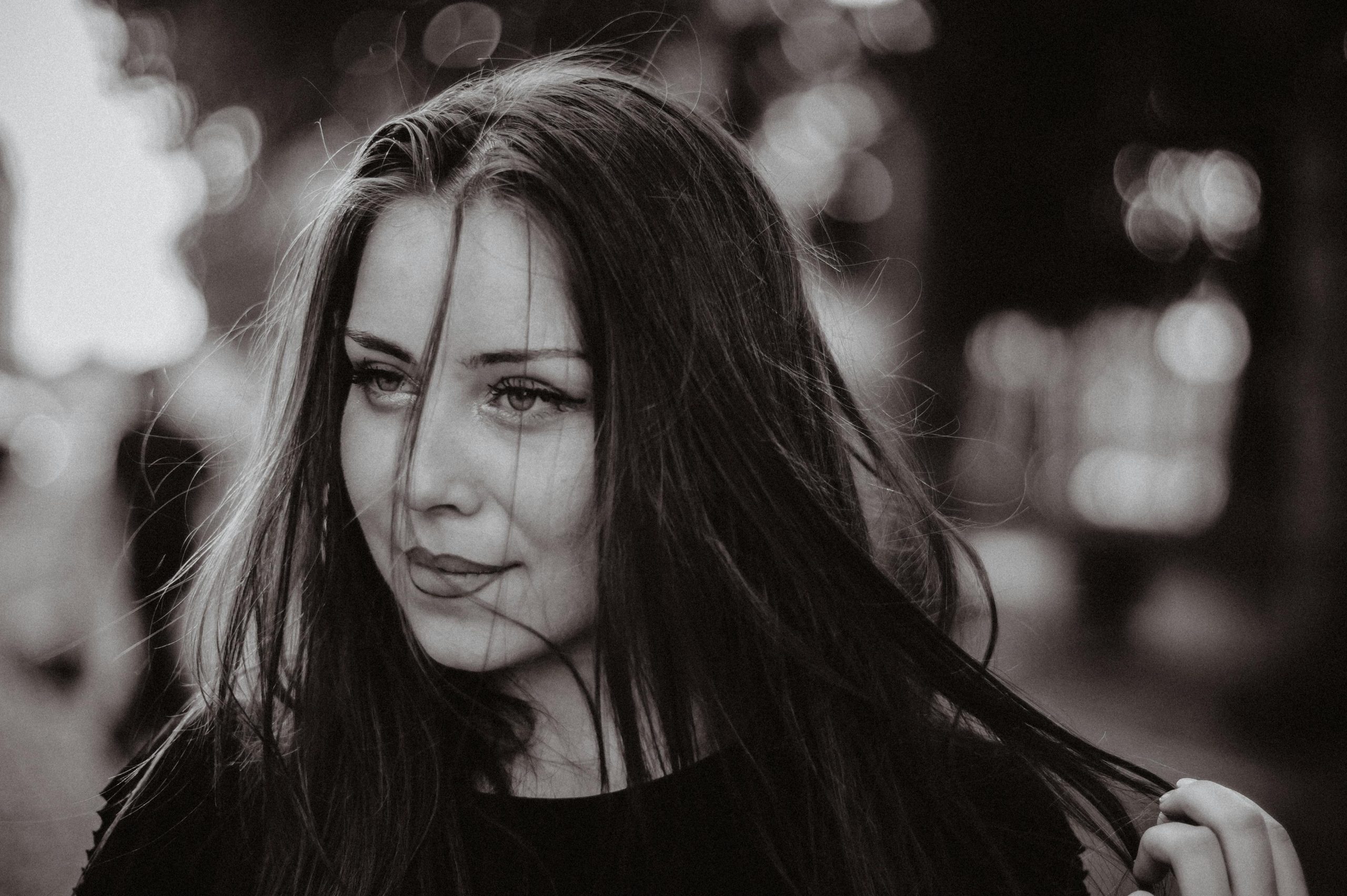 Elegant black and white portrait of a woman in a moody outdoor setting.