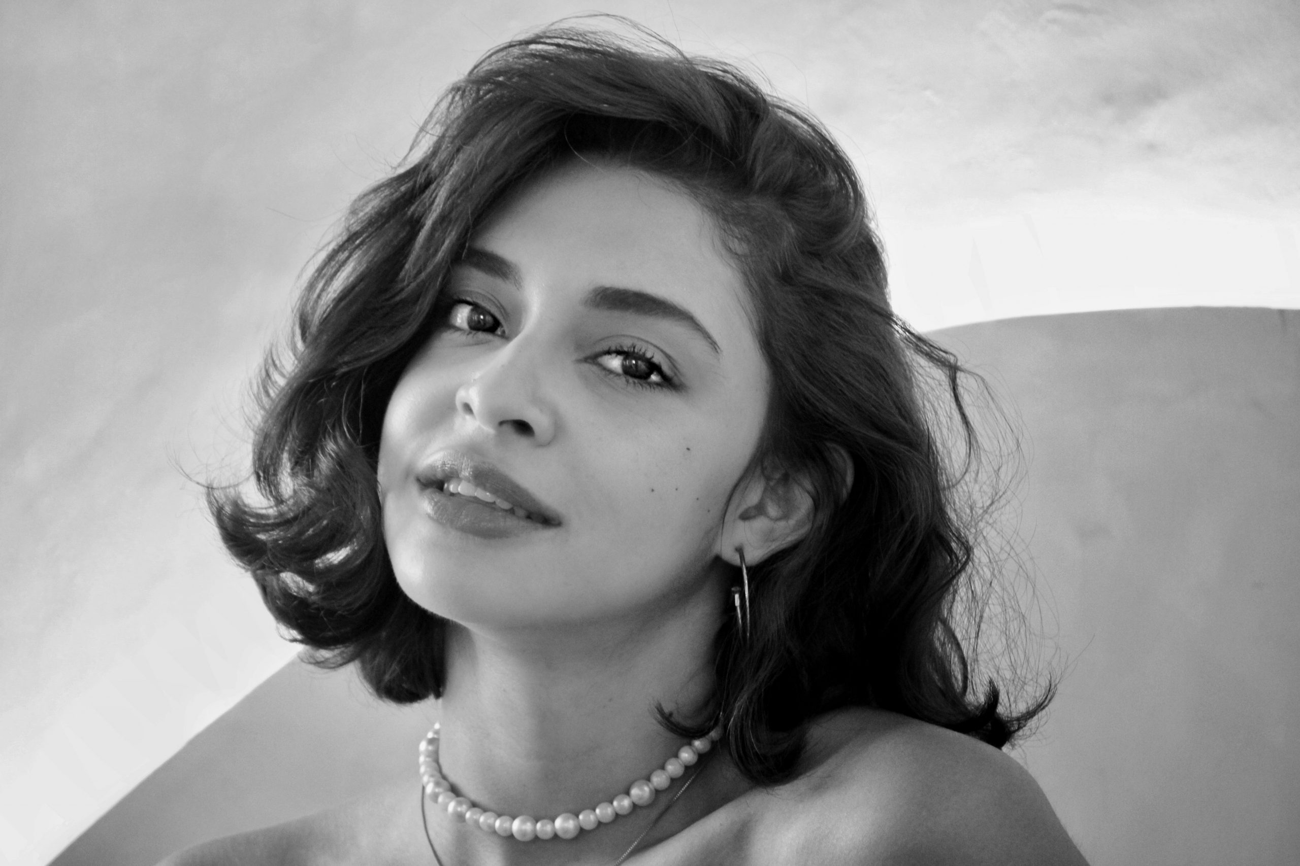 Black and white portrait of a woman with short hair and pearl necklace.